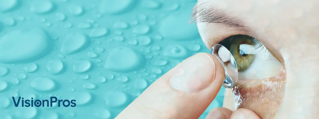 Close-up of a person placing a contact lens on their eye, with water droplets in the background and the VisionPros logo.