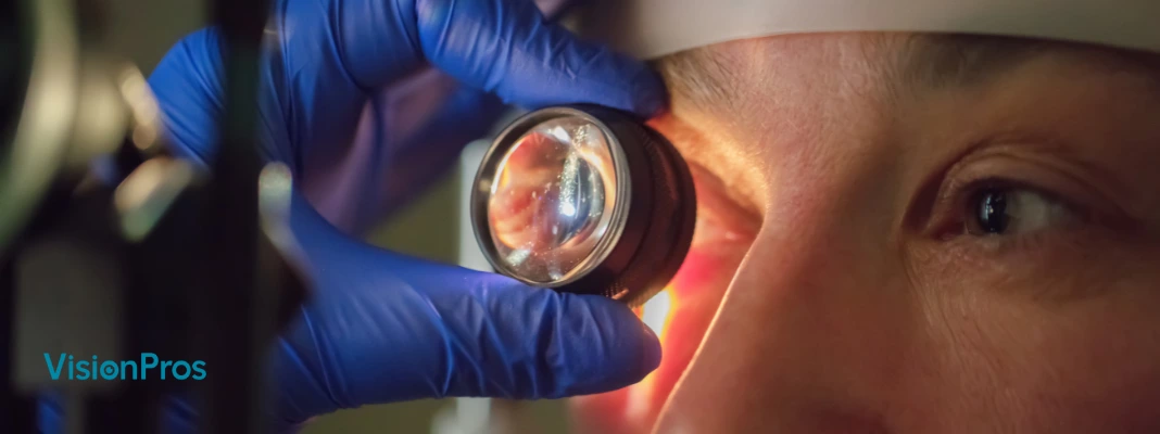 Optometrist examining a patient’s eye with a magnifying lens during an eye check-up, with VisionPros logo visible.