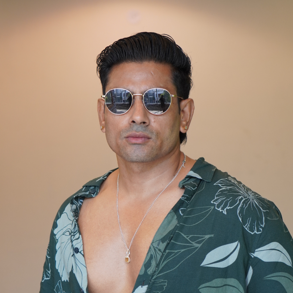 Man wearing aviator metal sunglasses with dark lenses and a casual open-collar shirt
