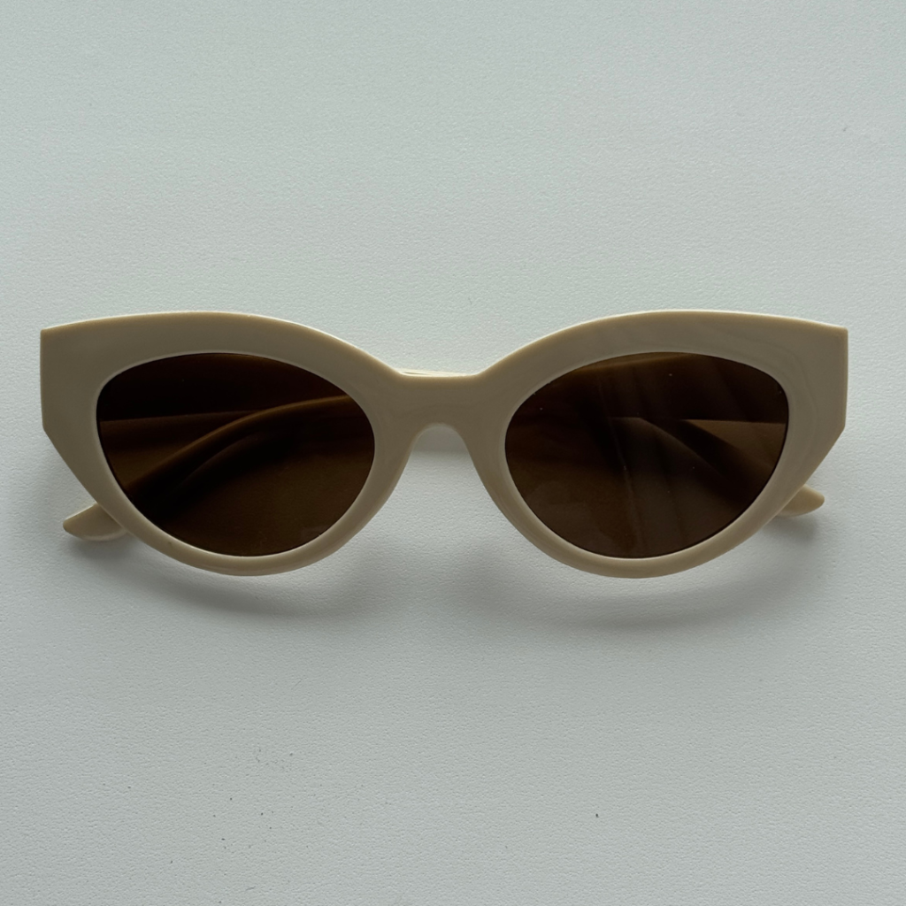 Beige cat-eye sunglasses with dark lenses on a neutral background