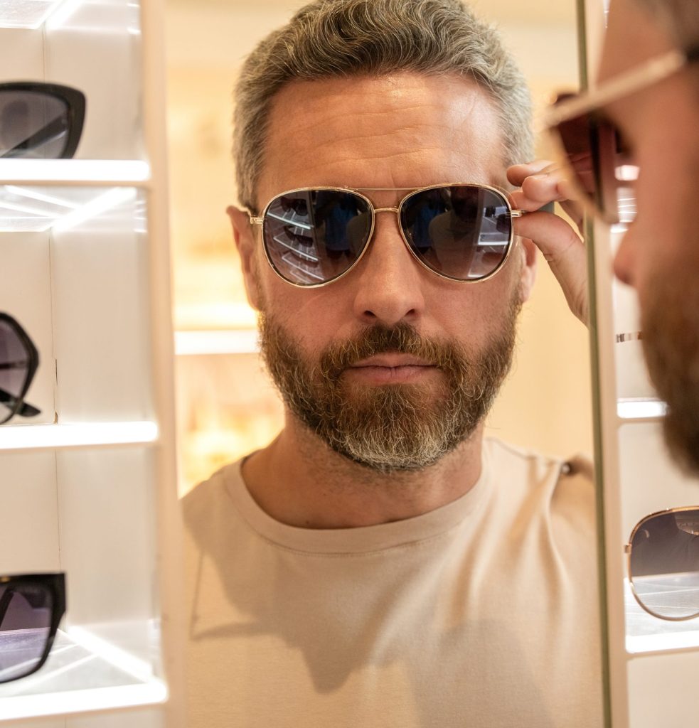 A man testing a pair of sunglasses in the mirror