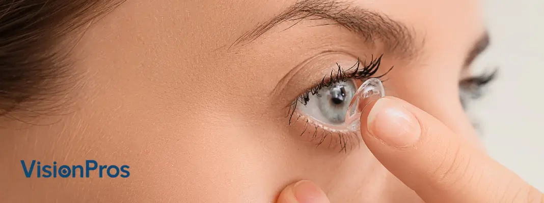 Close-up of a person placing a contact lens on an eye with VisionPros logo on the left