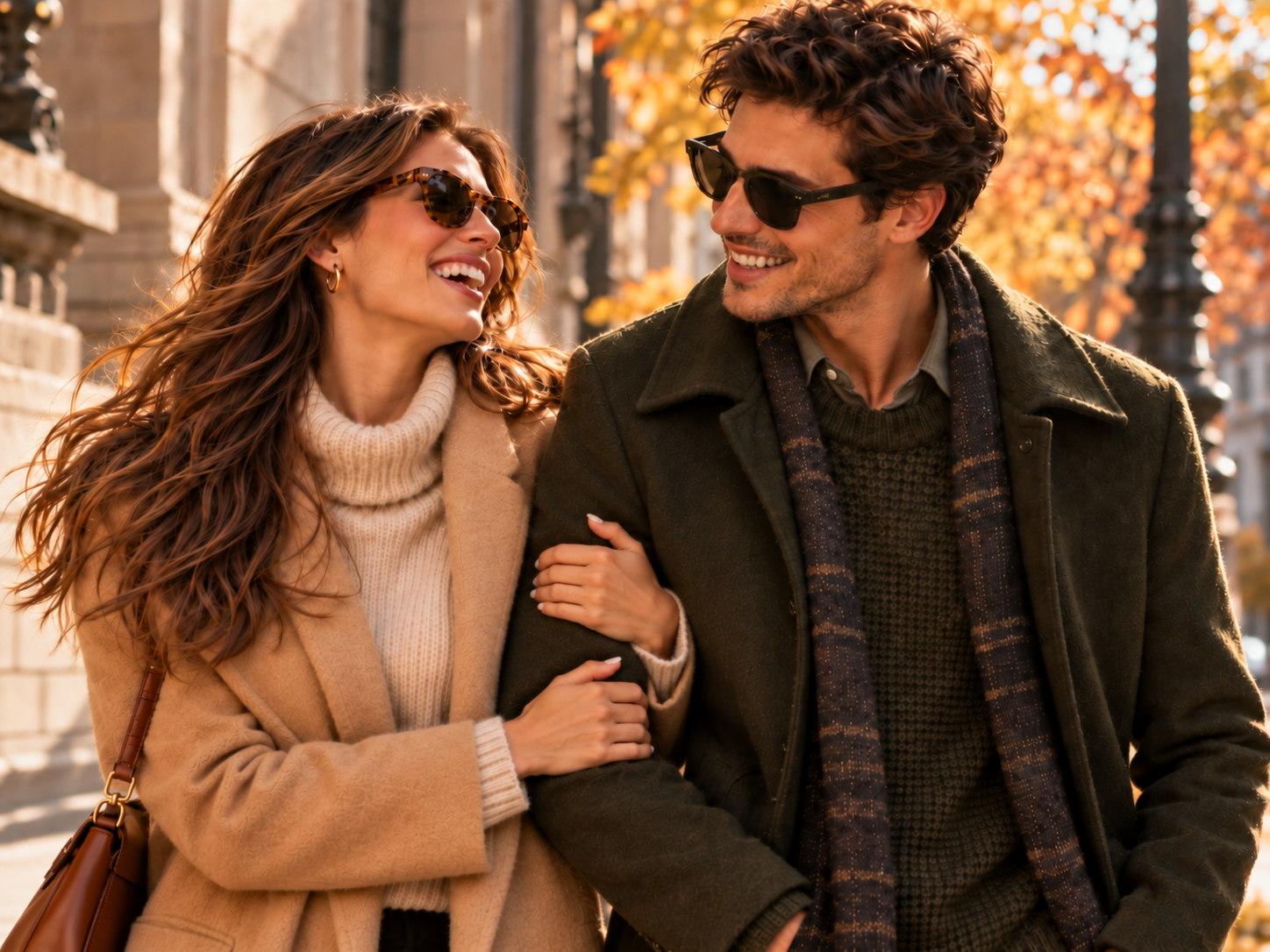 A woman and a man in camel and olive coats wearing tortoiseshell and dark sunglasses on an autumn street in an alternate view